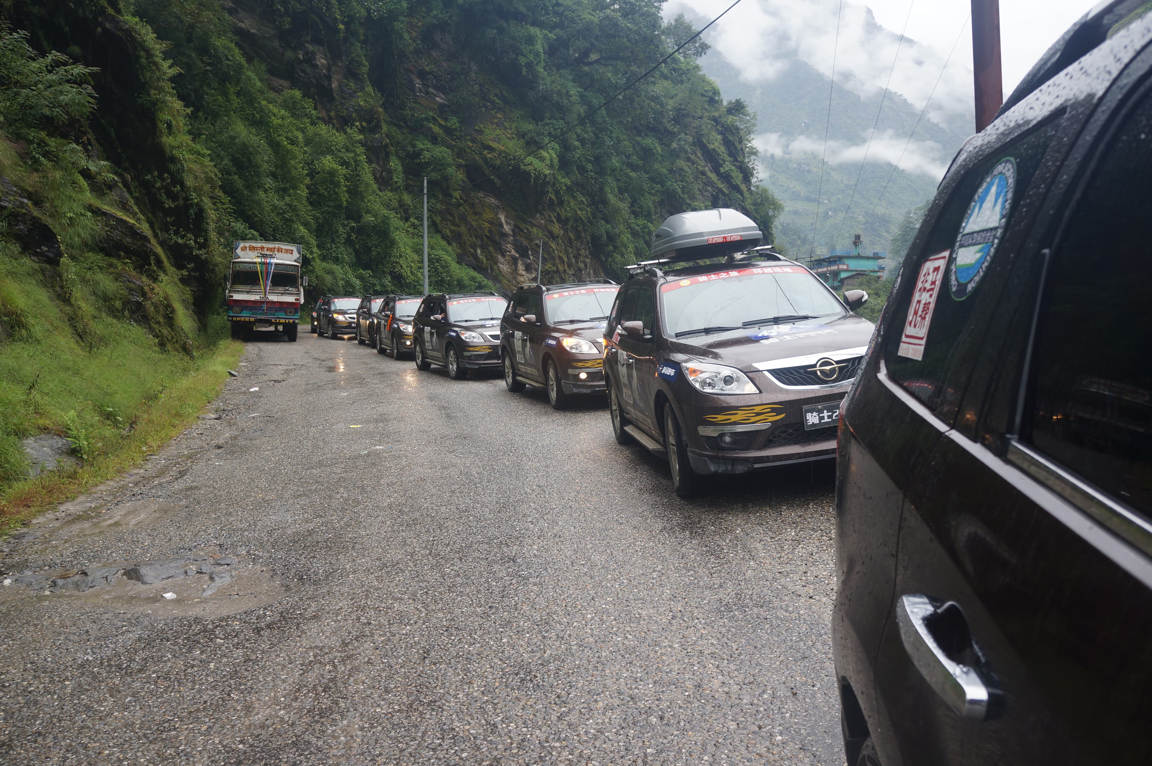 A convoy traveling along a wet mountain road between Nepal and China